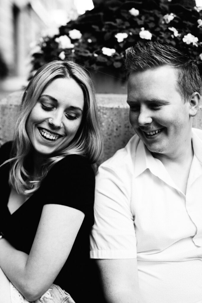 Abby and Allen Burch in black and white, laughing together while sitting next to each other