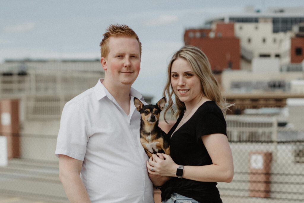 Allen and Abby with their dog, Taz, smiling at the camera on a summer day in Grand Rapids, Michigan